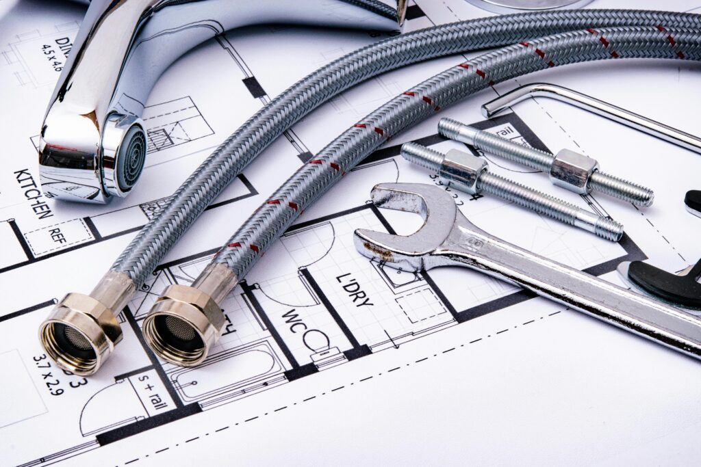 Close-up of plumbing tools and faucet on top of an architectural blueprint, perfect for hardware and construction themes.