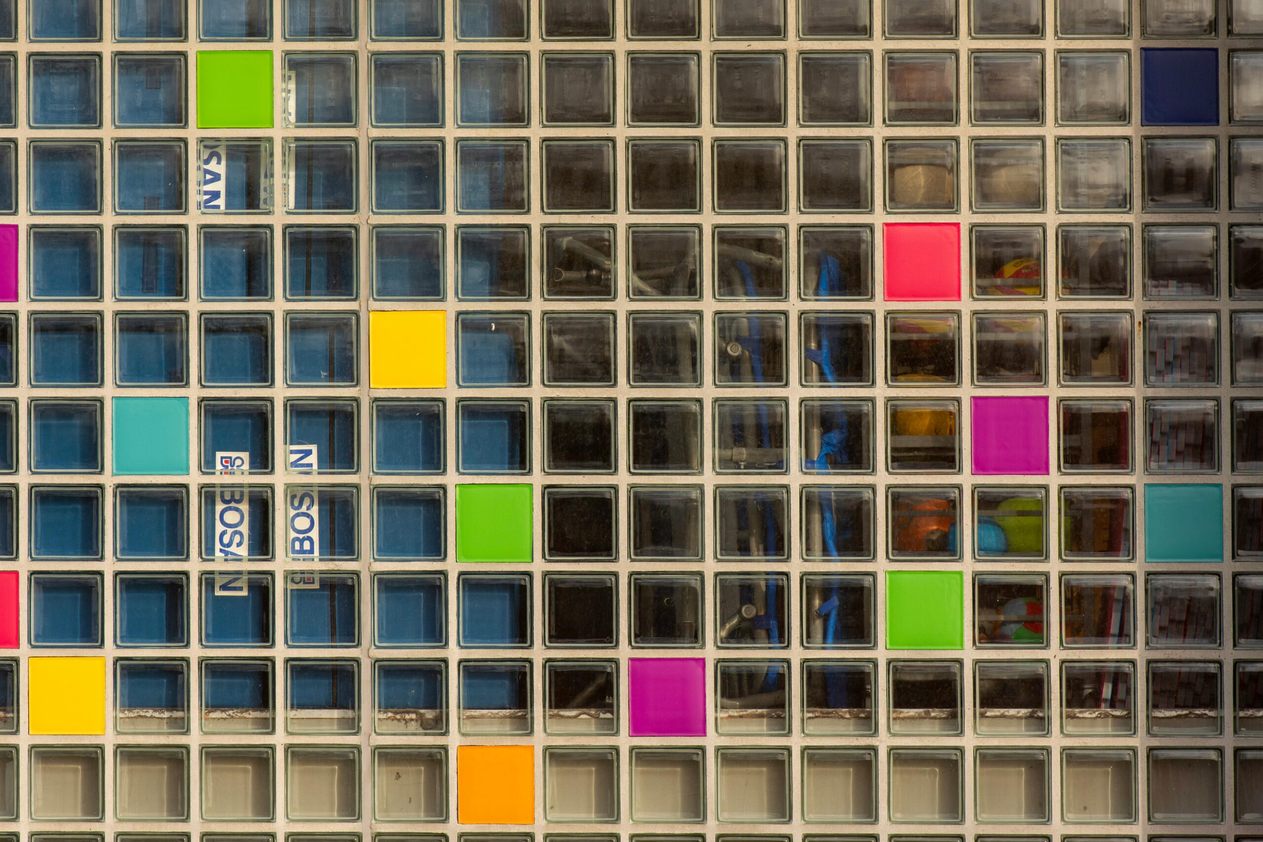 Colorful glass brick wall with a geometric pattern featuring various bright shades and abstract design elements.